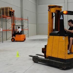: A photo showing two people operating forklifts indoors. Higher freight density shipments cost less to ship.